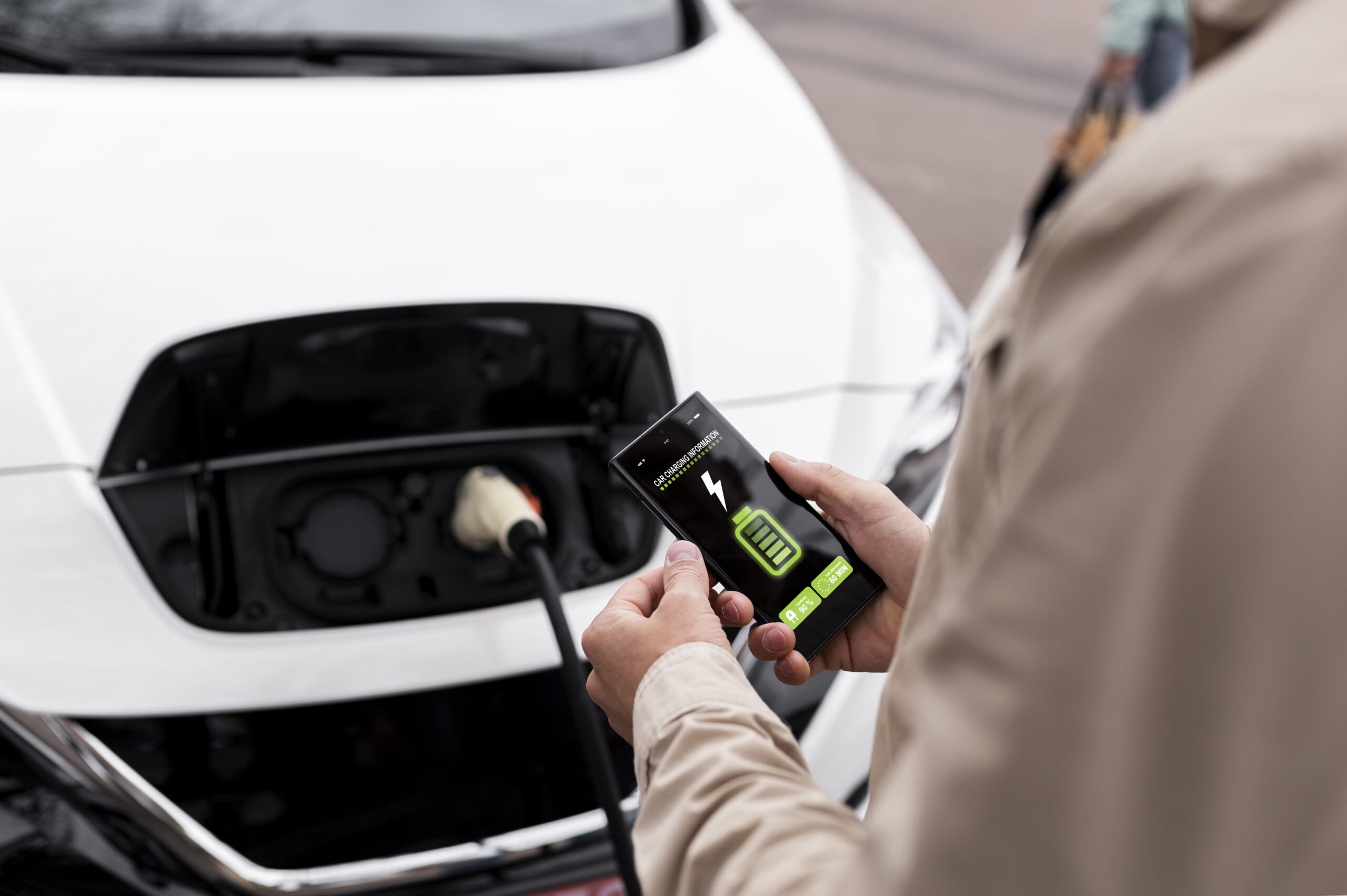 Elektrische auto Persoon laadt elektrische auto op en ziet batterij op telefoon.